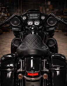Rear view of a black touring motorcycle with multiple integrated speakers around the seat and handlebars.