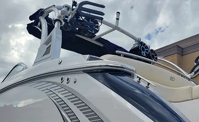 White boat with tower mounted speakers viewed from below against a cloudy sky.