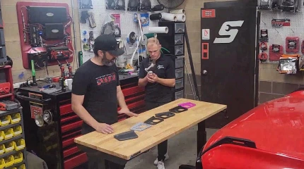 Car audio components including an amplifier speaker and wiring laid out on a workbench.